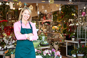 Woman working in florist standing outside store smiling